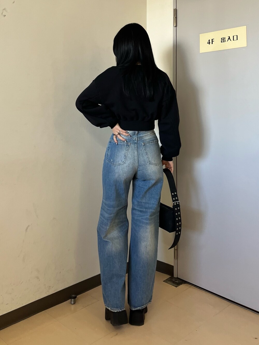 ブラック系のスウェット、ブルー系のデニムパンツ、ブラック系のショルダーバッグを着用したレディースの冬コーディネートの4枚目の写真