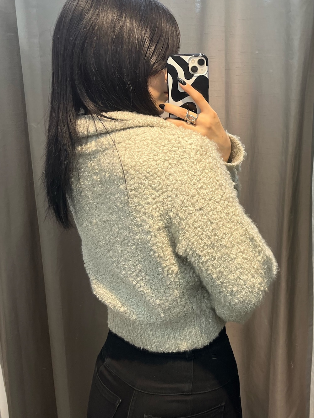 グレー系のニット/セーター、ブラック系のデニムパンツ、ブラック系のブーツを着用したレディースの秋コーディネートの4枚目の写真