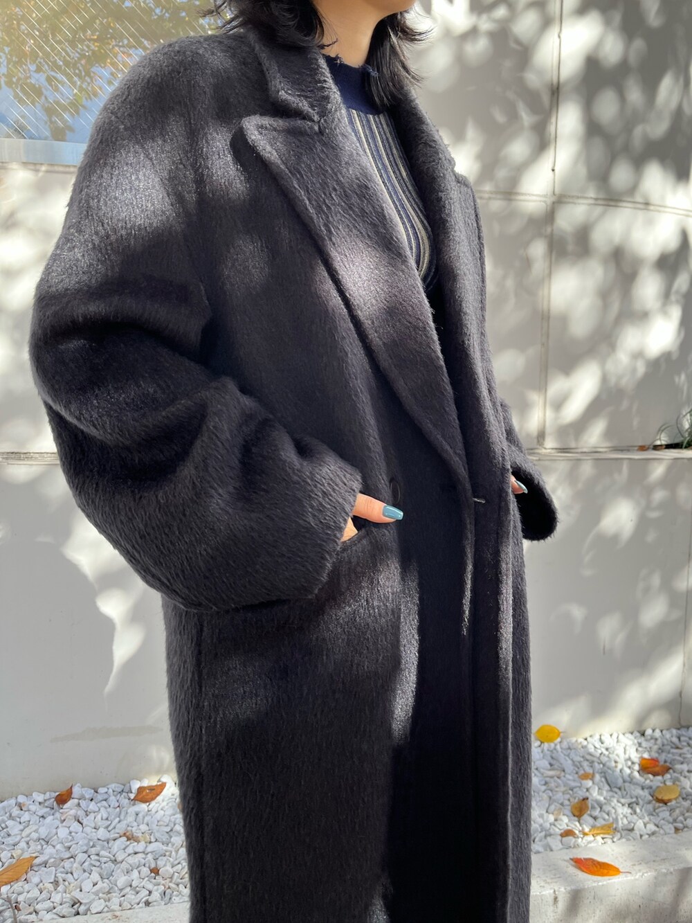 ブラック系のチェスターコート、その他のニット/セーター、ブルー系のデニムパンツを着用したレディースの冬コーディネートの4枚目の写真