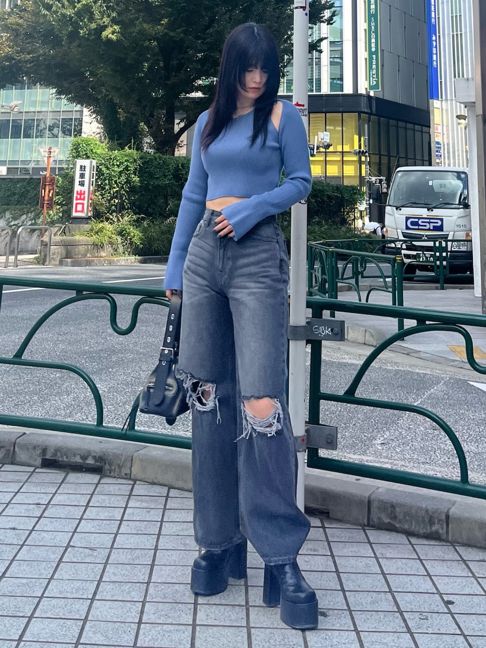 ブルー系のニット/セーター、グレー系のデニムパンツ、ブラック系のブーツを着用したレディースの秋コーディネートの2枚目の写真