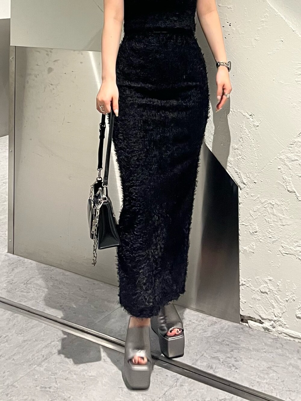 ブラック系のタンクトップ、ブラック系のスカート、ブラック系のショルダーバッグを着用したレディースの春コーディネートの6枚目の写真