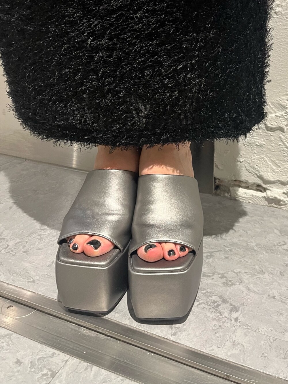 ブラック系のタンクトップ、ブラック系のスカート、ブラック系のショルダーバッグを着用したレディースの春コーディネートの7枚目の写真