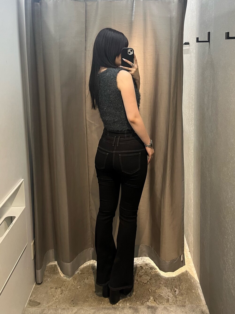 グレー系のタンクトップ、ブラック系のデニムパンツ、ブラック系のサンダルを着用したレディースの夏コーディネートの3枚目の写真