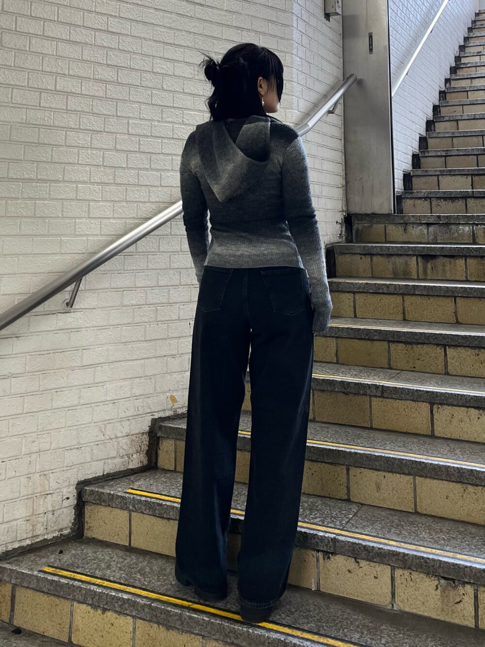 ブラック系のニット/セーター、ブラック系のデニムパンツ、ブラック系のブーツを着用したレディースの冬コーディネートの3枚目の写真