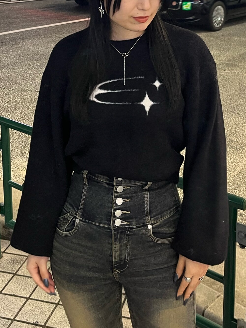 ブラック系のニット/セーター、ブルー系のデニムパンツ、ブラック系のブーツを着用したレディースの秋コーディネートの5枚目の写真