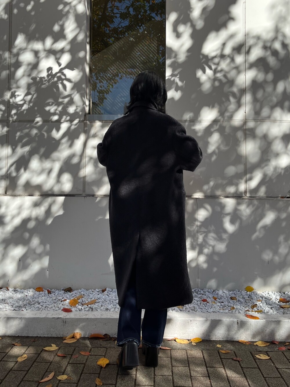 ブラック系のチェスターコート、その他のニット/セーター、ブルー系のデニムパンツを着用したレディースの冬コーディネートの3枚目の写真