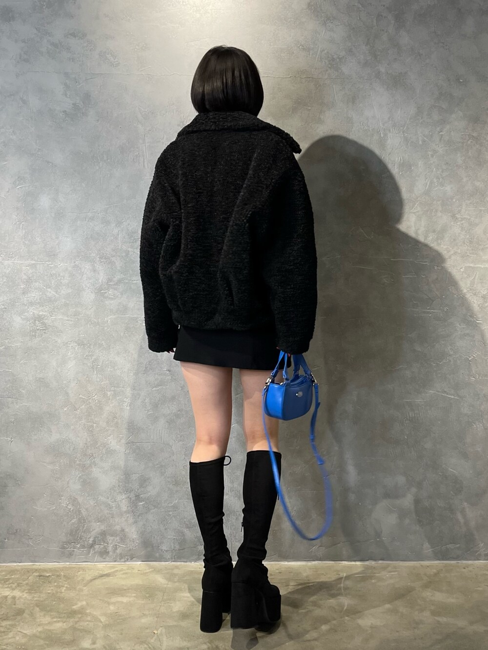 ブラック系のブルゾン、ブルー系のニット/セーター、ブラック系のスカートを着用したレディースの冬コーディネートの2枚目の写真