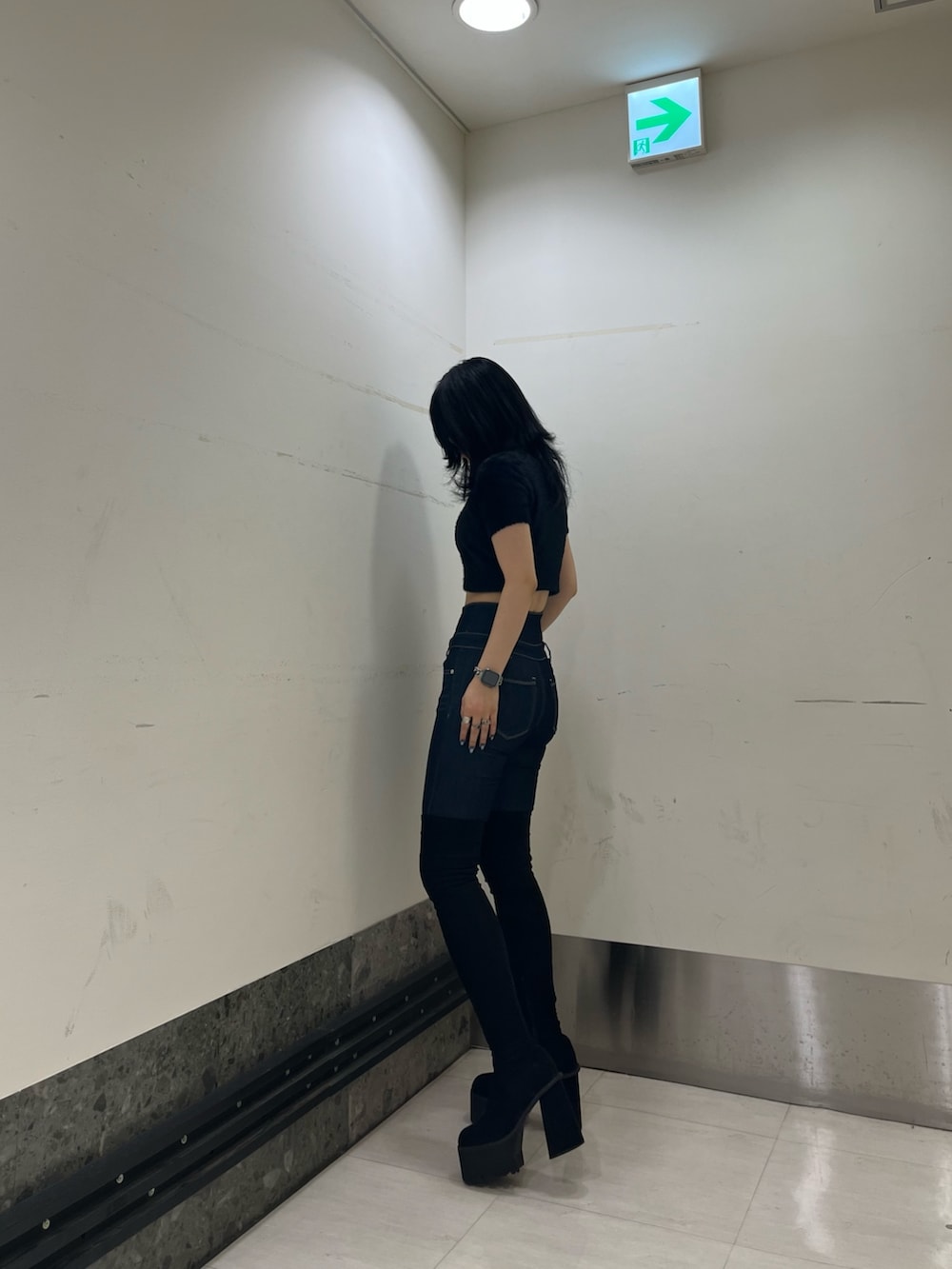 ブラック系のニット/セーター、ブルー系のデニムパンツ、ブラック系のブーツを着用したレディースの夏コーディネートの4枚目の写真