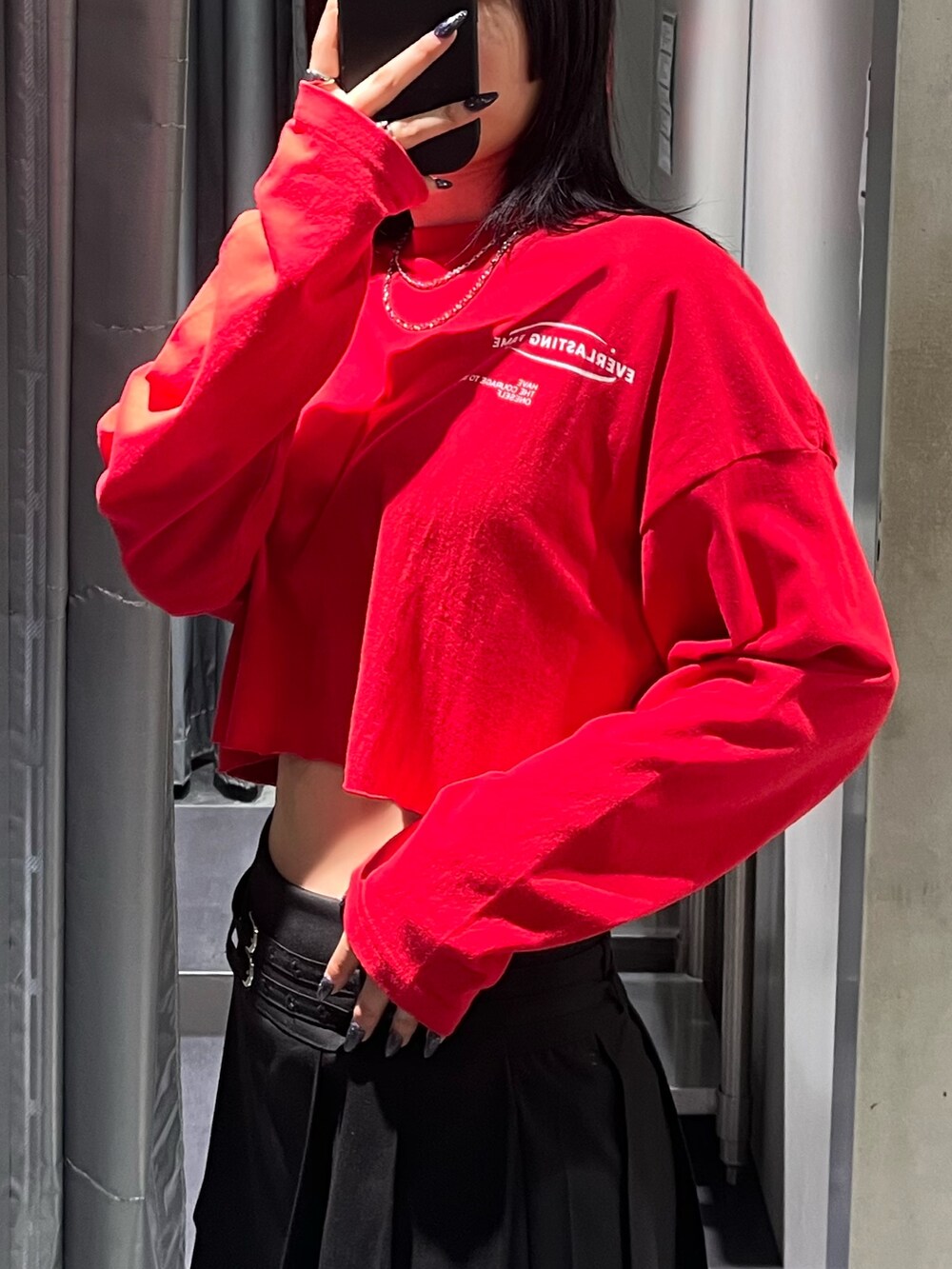 レッド系のTシャツ/カットソー、ブラック系のスカート、ブラック系のブーツを着用したレディースの秋コーディネートの5枚目の写真