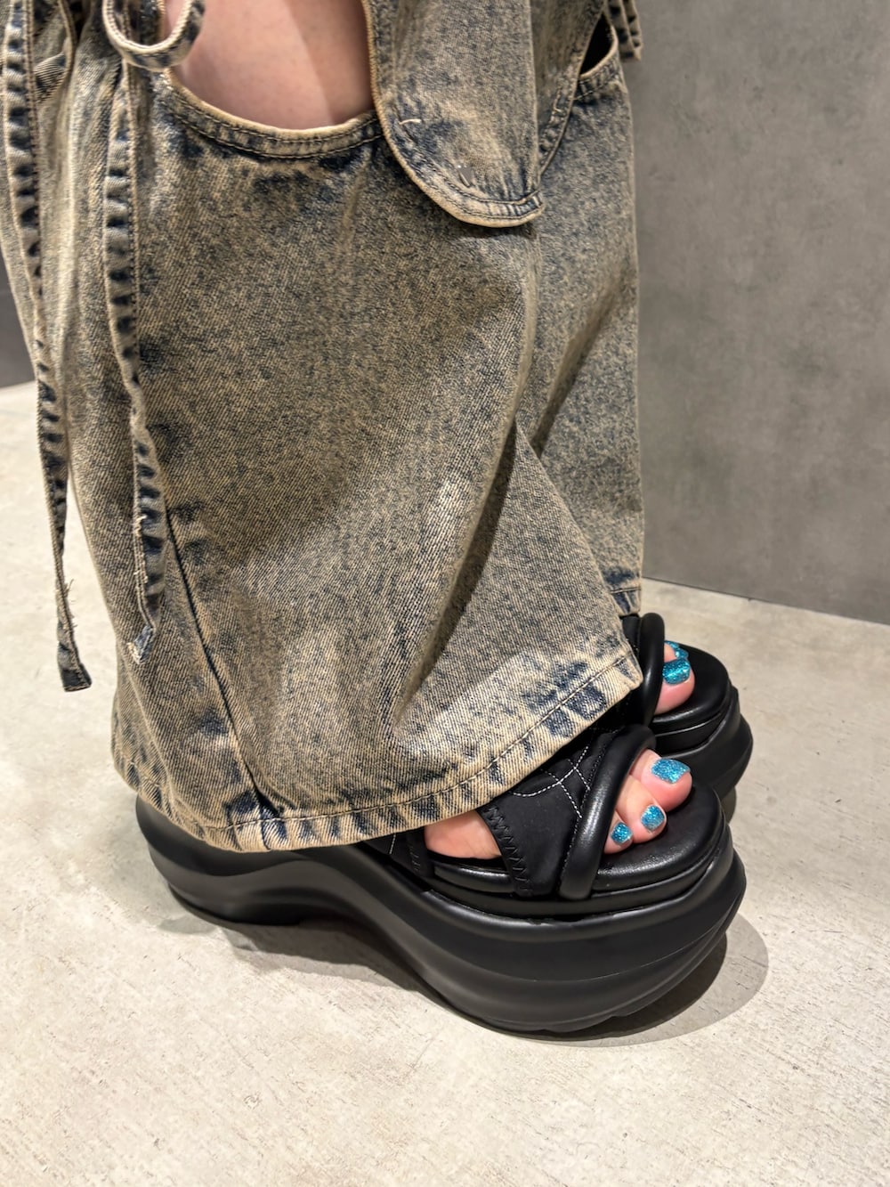 ブラック系のTシャツ/カットソー、ブルー系のデニムパンツ、ブラック系のサンダルを着用したレディースの春コーディネートの6枚目の写真