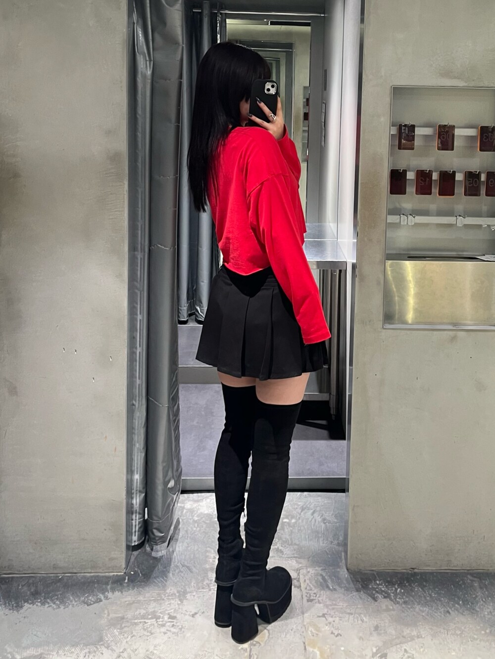 レッド系のTシャツ/カットソー、ブラック系のスカート、ブラック系のブーツを着用したレディースの秋コーディネートの3枚目の写真