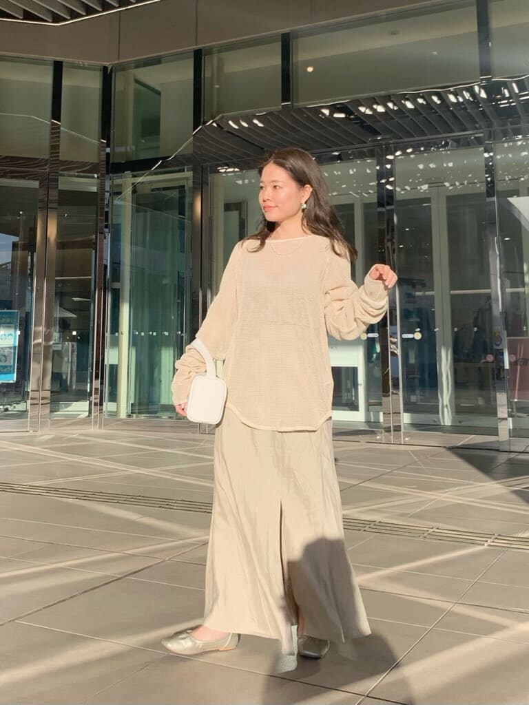 ホワイト系のハンドバッグ、ベージュ系のスカート、ホワイト系のTシャツ/カットソーを着用したレディースの春コーディネートの2枚目の写真