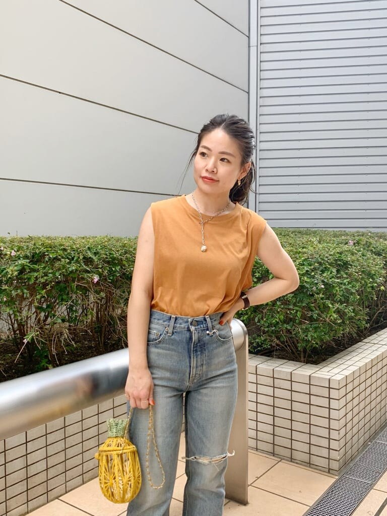 イエロー系のショルダーバッグ、ブルー系のデニムパンツ、ブラウン系のサンダルを着用したレディースの夏コーディネートの3枚目の写真