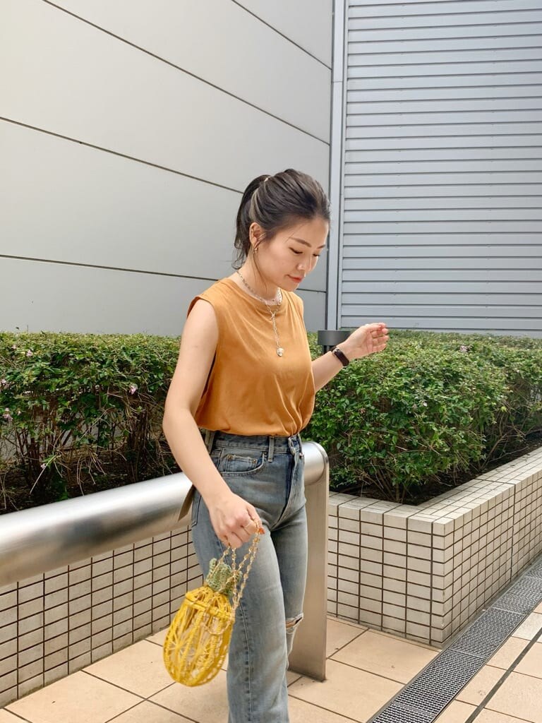 イエロー系のショルダーバッグ、ブルー系のデニムパンツ、ブラウン系のサンダルを着用したレディースの夏コーディネートの4枚目の写真