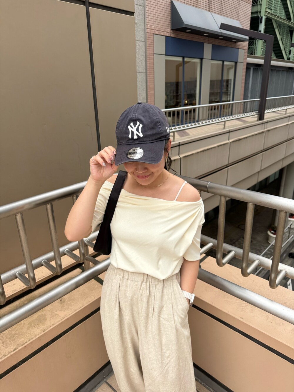 ホワイト系のTシャツ/カットソー、ベージュ系のその他パンツ、ブラック系のハンドバッグを着用したレディースの夏コーディネートの6枚目の写真