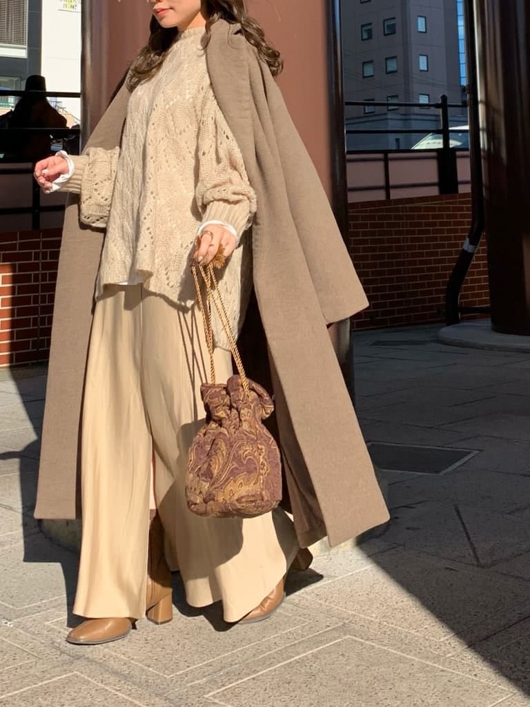 ベージュ系のスカート、ベージュ系のニット/セーター、ブラウン系のハンドバッグを着用したレディースの秋コーディネートの3枚目の写真