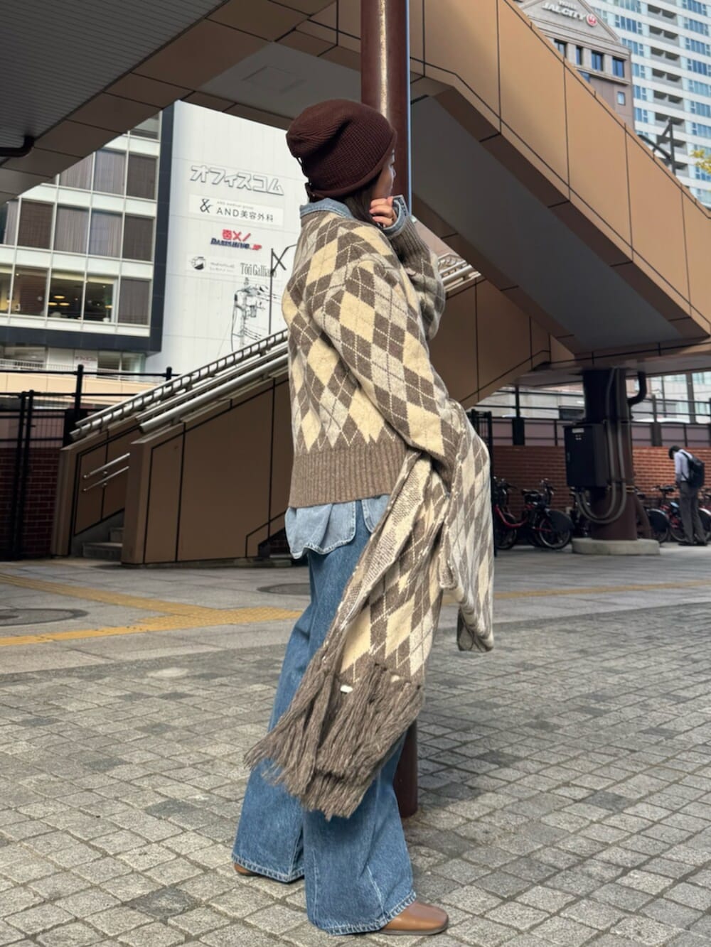 ベージュ系のニット/セーター、ブルー系のシャツ/ブラウス、ブルー系のデニムパンツを着用したレディースの秋コーディネートの2枚目の写真