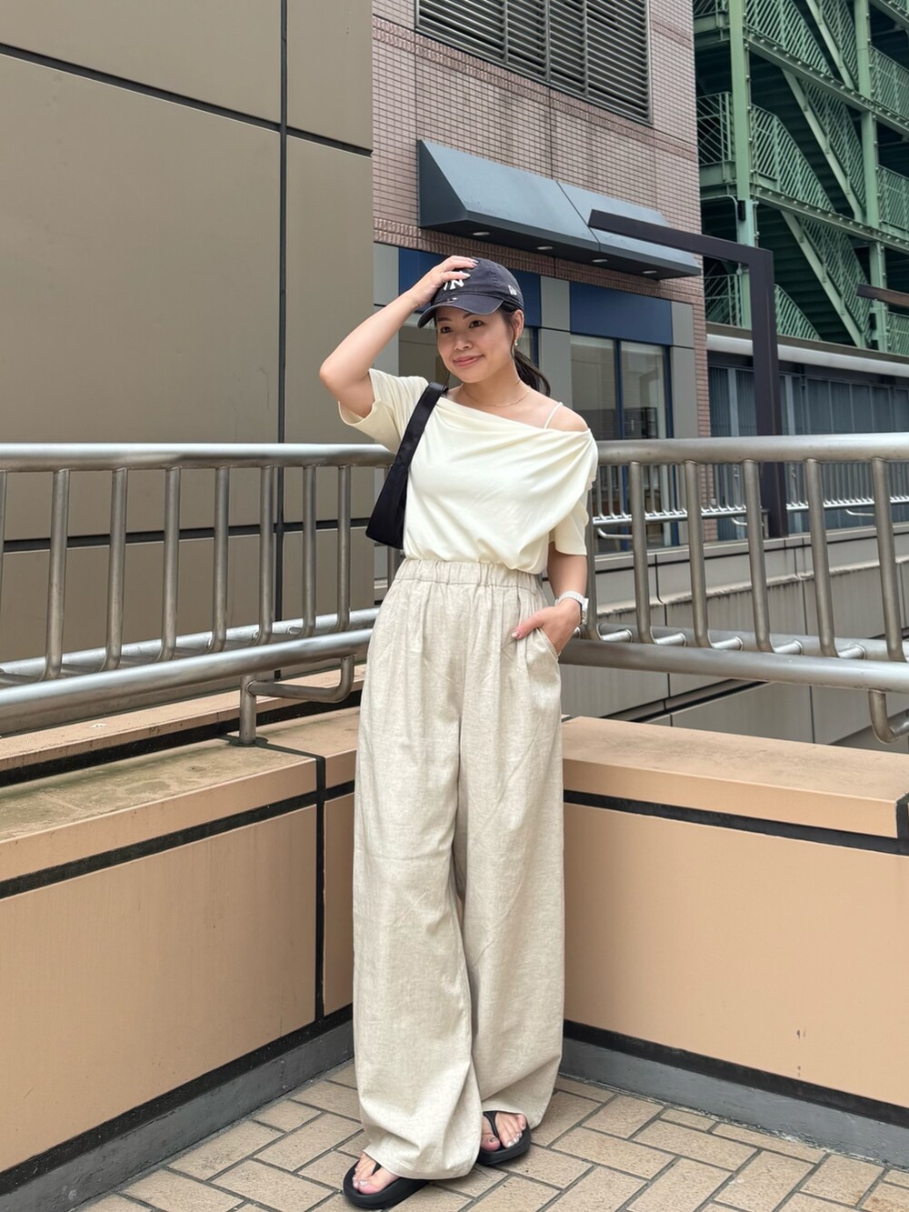 ホワイト系のTシャツ/カットソー、ベージュ系のその他パンツ、ブラック系のハンドバッグを着用したレディースの夏コーディネートの2枚目の写真