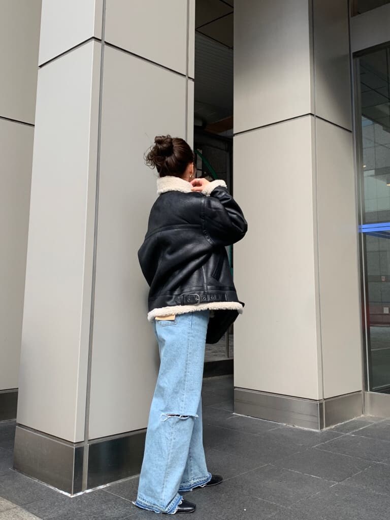 レッド系のニット/セーター、ブラック系のクラッチバッグ、ブラック系のムートンコートを着用したレディースの秋コーディネートの2枚目の写真