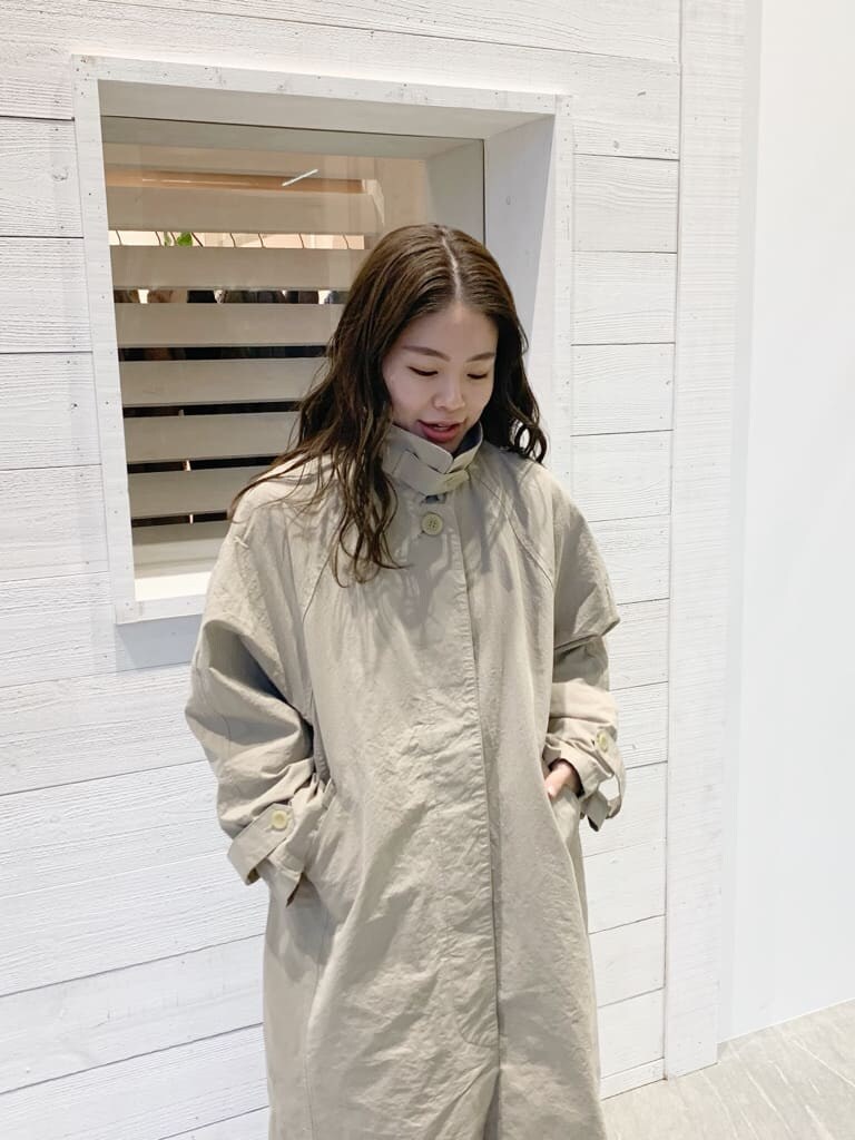 ベージュ系のステンカラーコートを着用したレディースの春コーディネートの3枚目の写真