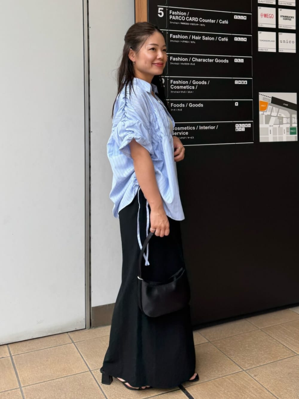 ブラック系のハンドバッグ、ブルー系のシャツ/ブラウス、ブラック系のスカートを着用したレディースの夏コーディネートの3枚目の写真