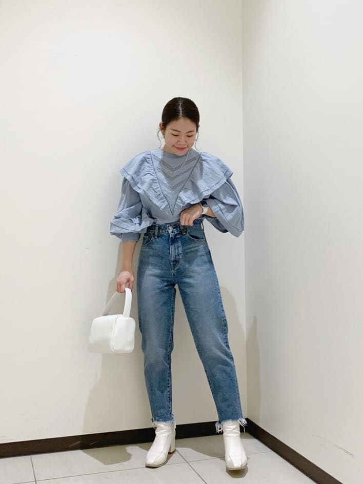 ブルー系のデニムパンツ、ブルー系のシャツ/ブラウス、ホワイト系のハンドバッグを着用したレディースの冬コーディネートの2枚目の写真