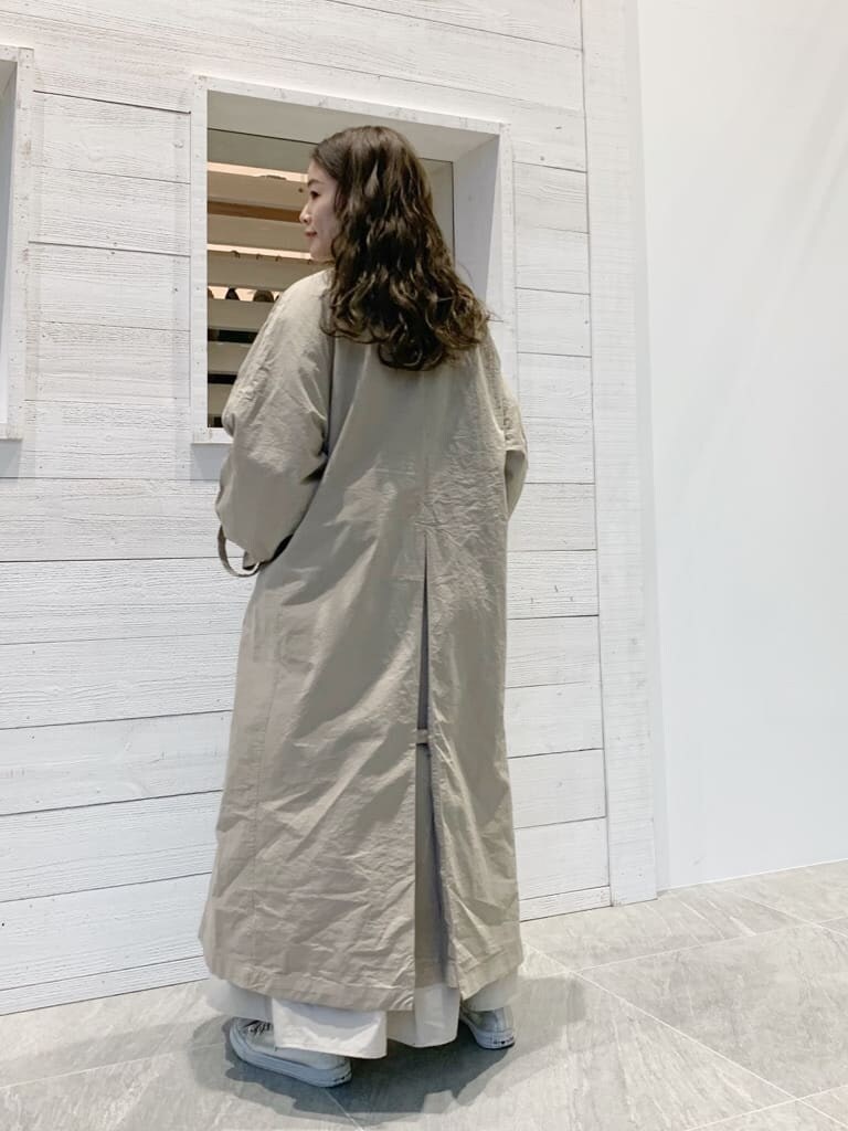 ベージュ系のステンカラーコートを着用したレディースの春コーディネートの2枚目の写真