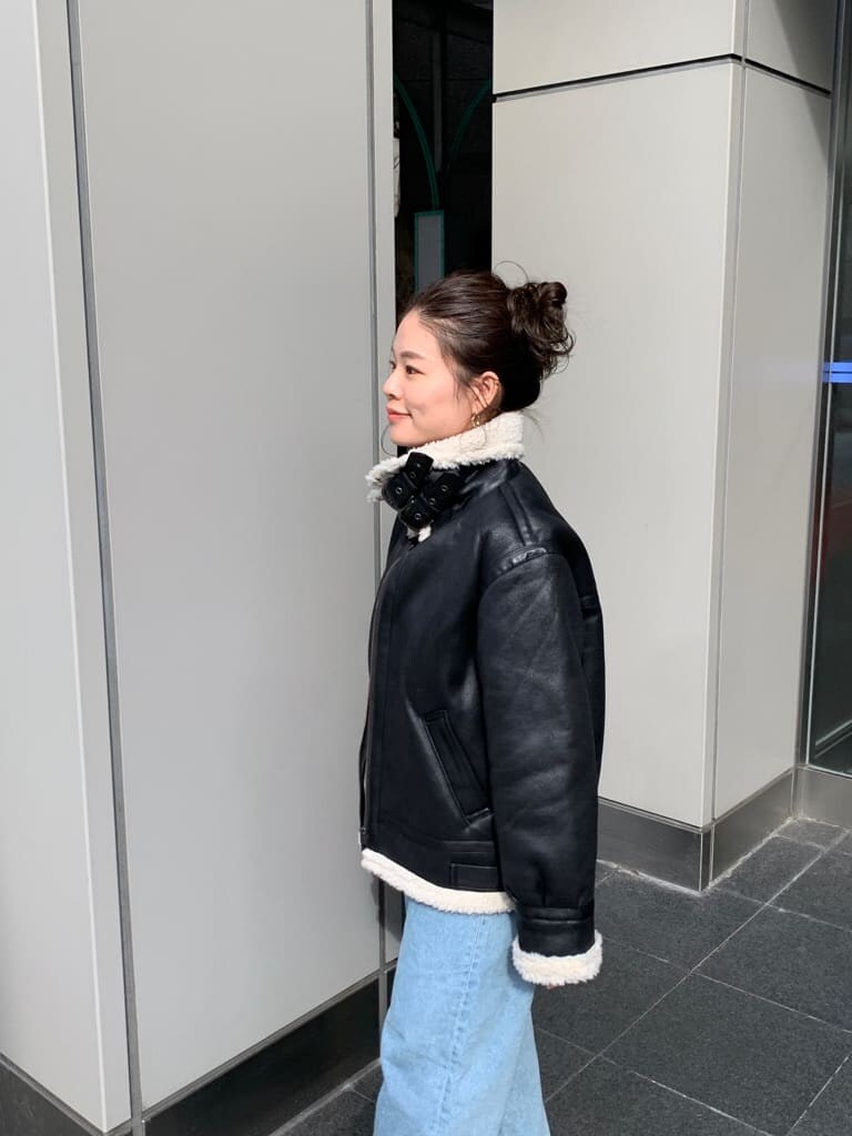 レッド系のニット/セーター、ブラック系のクラッチバッグ、ブラック系のムートンコートを着用したレディースの秋コーディネートの4枚目の写真