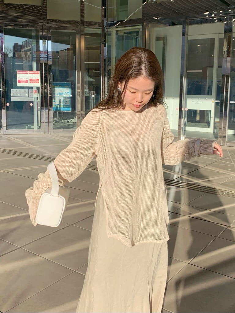 ホワイト系のハンドバッグ、ベージュ系のスカート、ホワイト系のTシャツ/カットソーを着用したレディースの春コーディネートの7枚目の写真