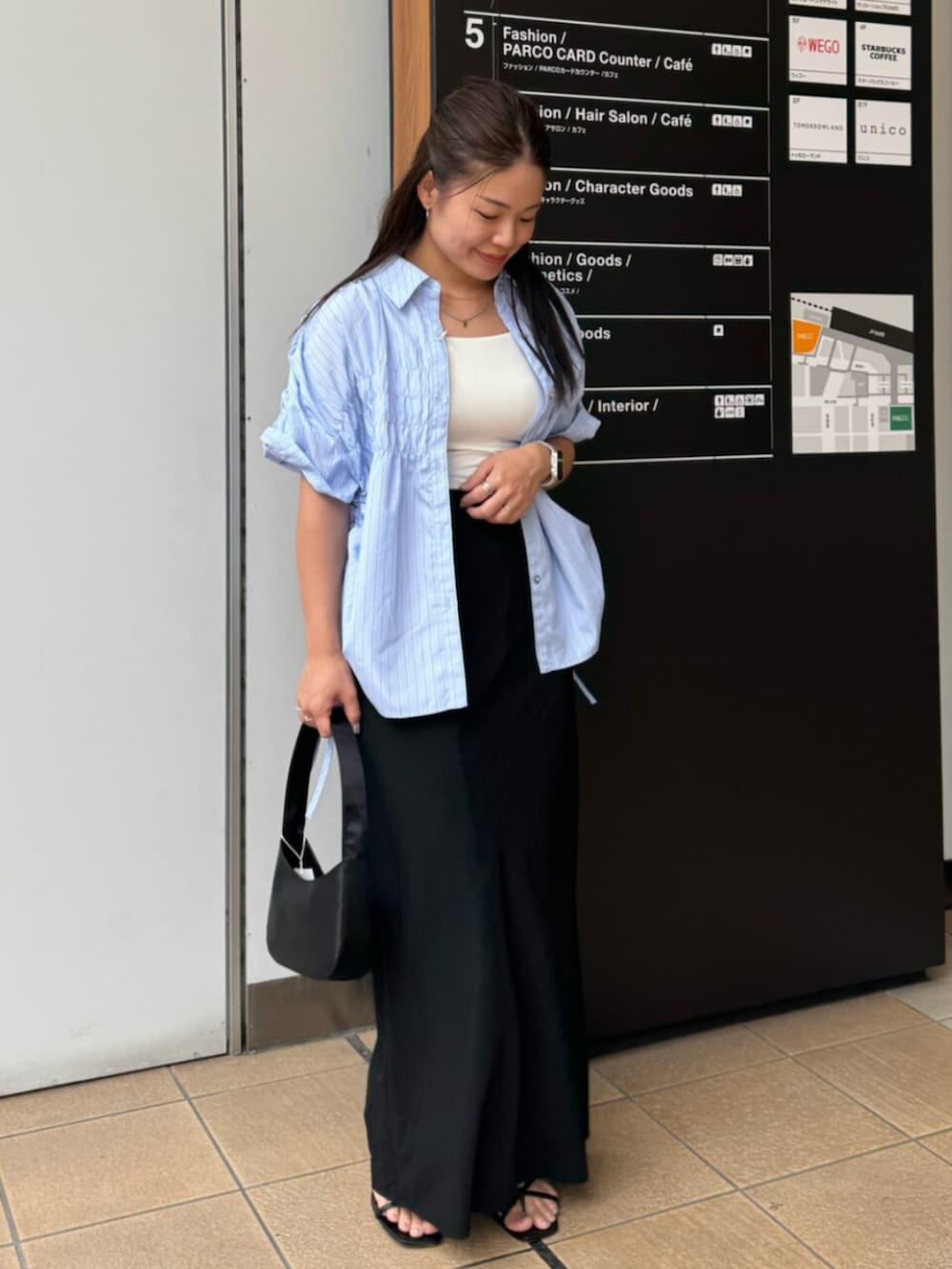 ブラック系のハンドバッグ、ブルー系のシャツ/ブラウス、ブラック系のスカートを着用したレディースの夏コーディネートの2枚目の写真