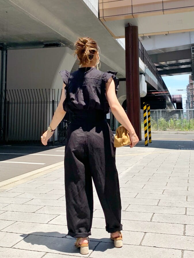 ブラック系のその他パンツ、ベージュ系のクラッチバッグ、ブラウン系のサンダルを着用したレディースの夏コーディネートの2枚目の写真