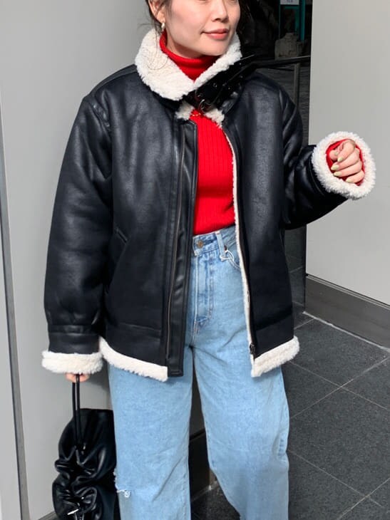 レッド系のニット/セーター、ブラック系のクラッチバッグ、ブラック系のムートンコートを着用したレディースの秋コーディネートの6枚目の写真