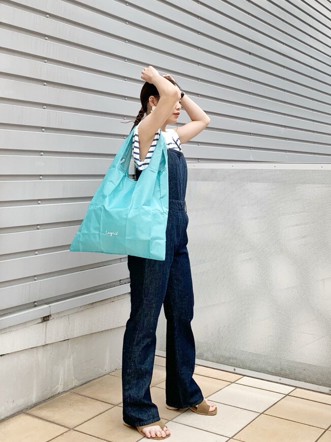 ブルー系のつなぎ/オールインワン、ブラウン系のサンダル、ブルー系のハンドバッグを着用したレディースの春コーディネートの2枚目の写真