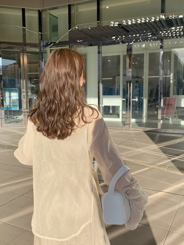 ホワイト系のハンドバッグ、ベージュ系のスカート、ホワイト系のTシャツ/カットソーを着用したレディースの春コーディネートの6枚目の写真