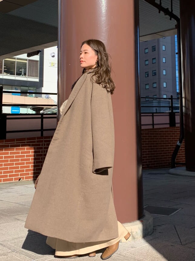 ベージュ系のスカート、ベージュ系のニット/セーター、ブラウン系のハンドバッグを着用したレディースの秋コーディネートの2枚目の写真