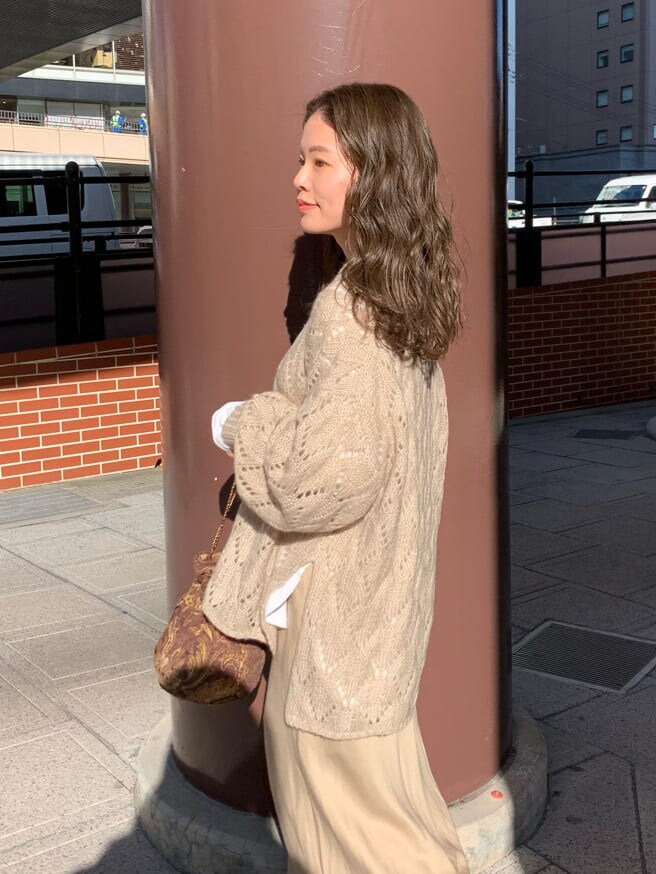 ブラウン系のハンドバッグ、ベージュ系のスカート、ベージュ系のニット/セーターを着用したレディースの秋コーディネートの2枚目の写真