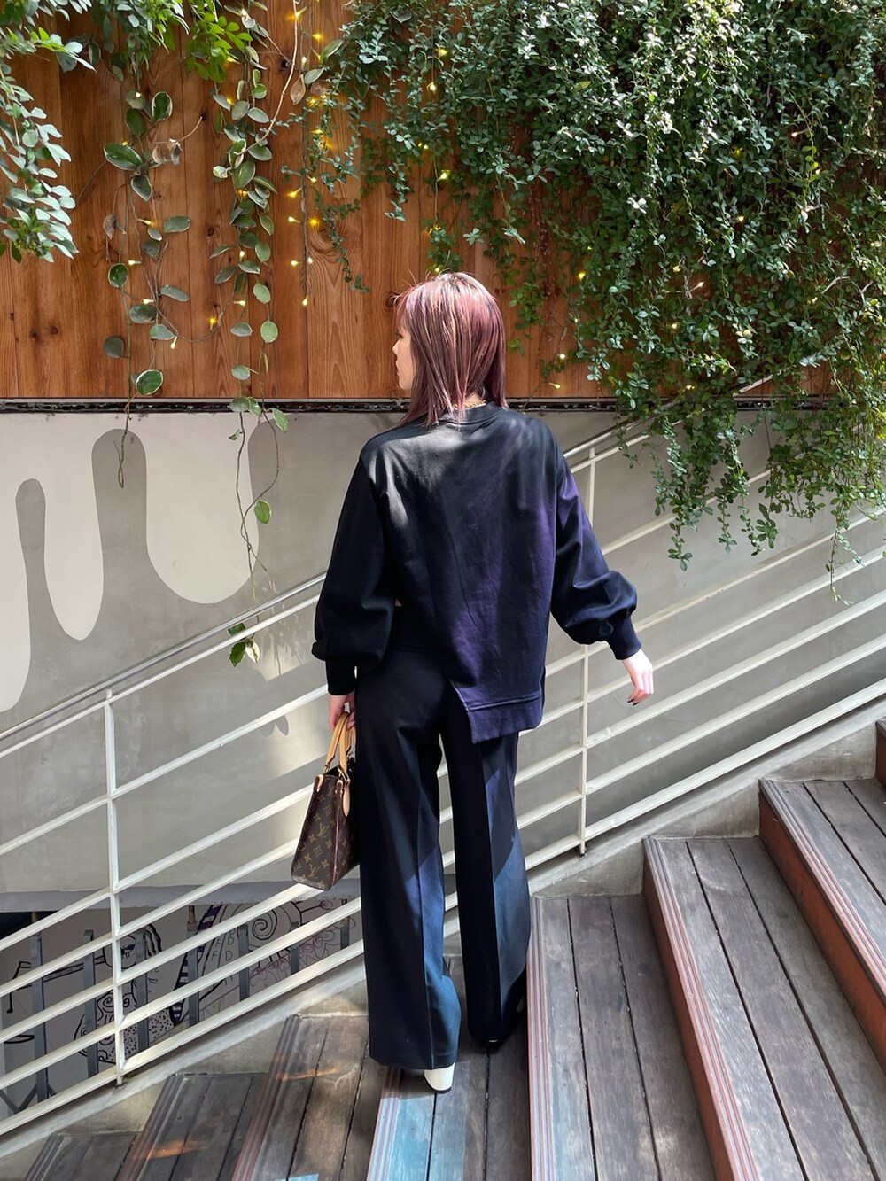 ブラック系のTシャツ/カットソー、ブラック系のスラックス、ホワイト系のサンダルを着用したレディースの春コーディネートの4枚目の写真