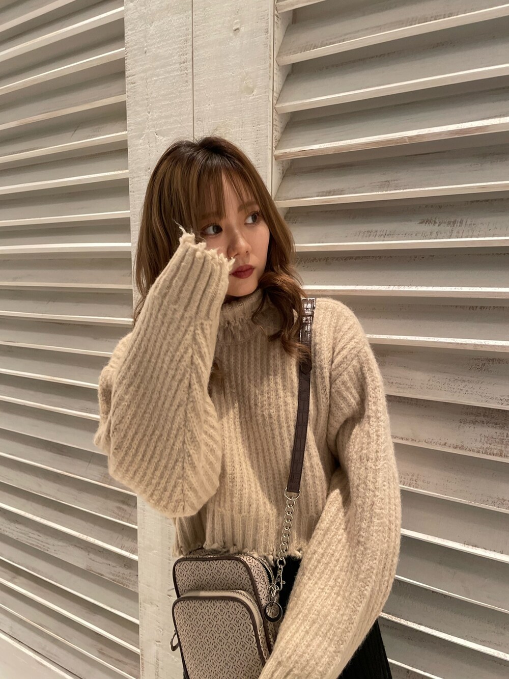 ホワイト系のニット/セーター、ブラック系のブーツ、その他のショルダーバッグを着用したレディースの秋コーディネートの4枚目の写真