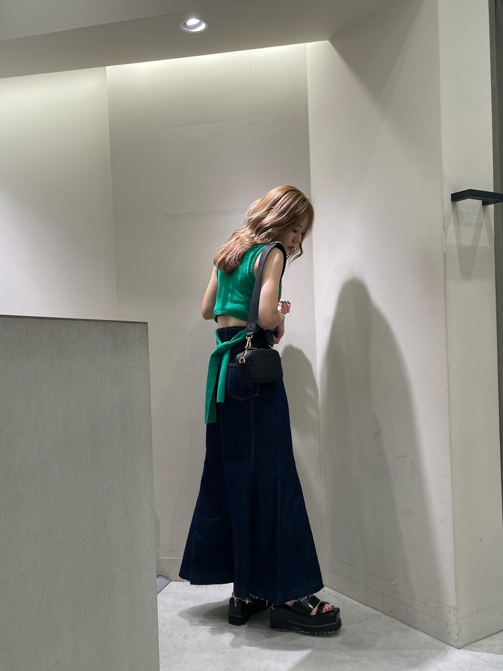 ブラック系のサンダル、ブラック系のショルダーバッグ、グリーン系のタンクトップを着用したレディースの夏コーディネートの3枚目の写真