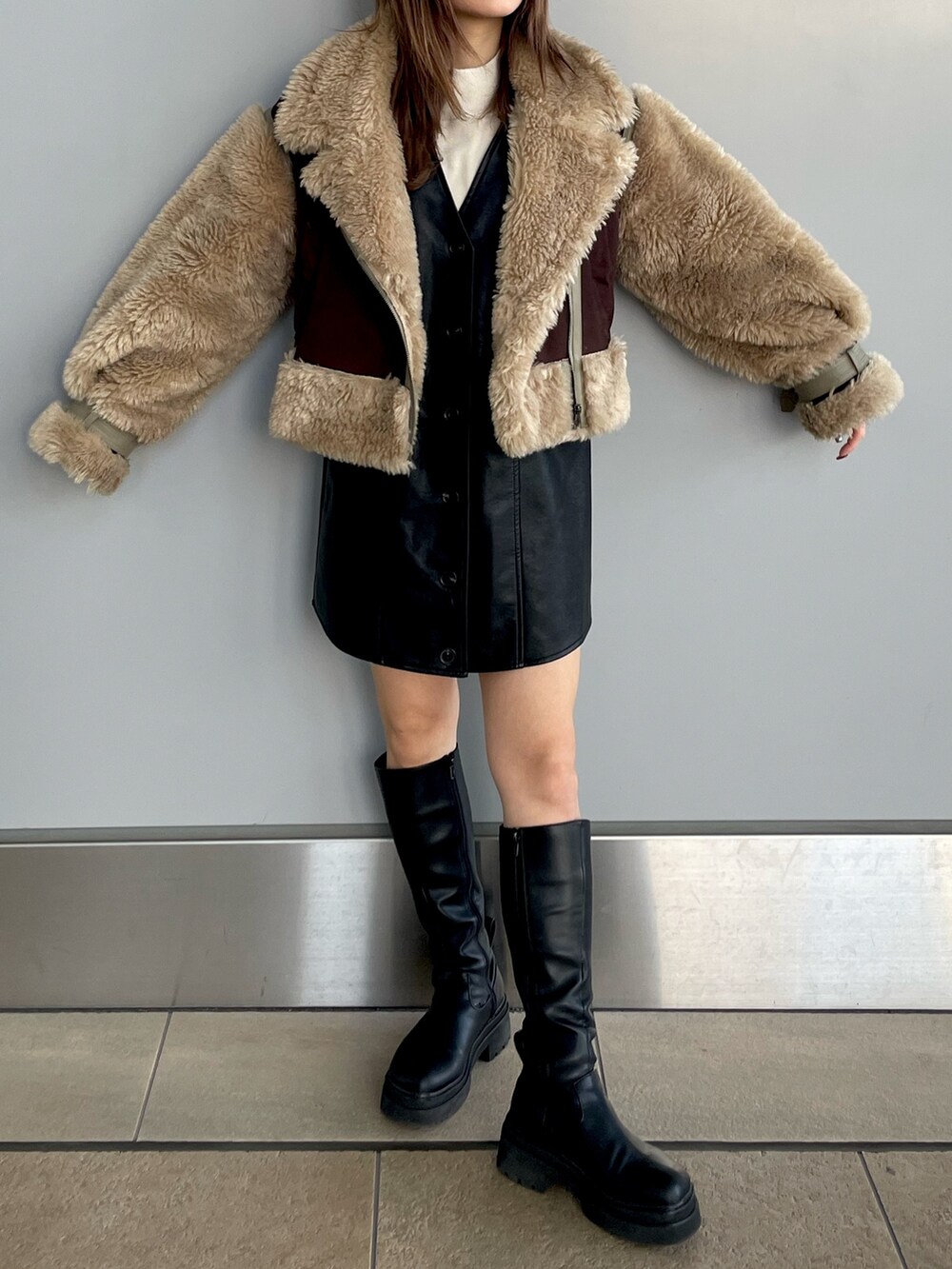 ブラック系のワンピース、ホワイト系のニット/セーター、ブラウン系のムートンコートを着用したレディースの冬コーディネートの3枚目の写真