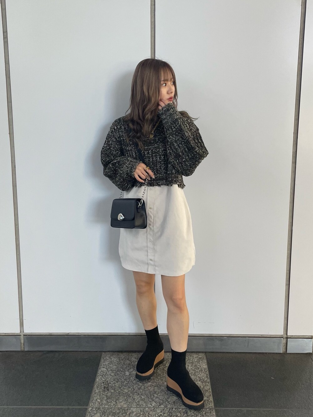 グリーン系のワンピース、ブラック系のショルダーバッグ、ブラック系のブーツを着用したレディースの秋コーディネートの2枚目の写真