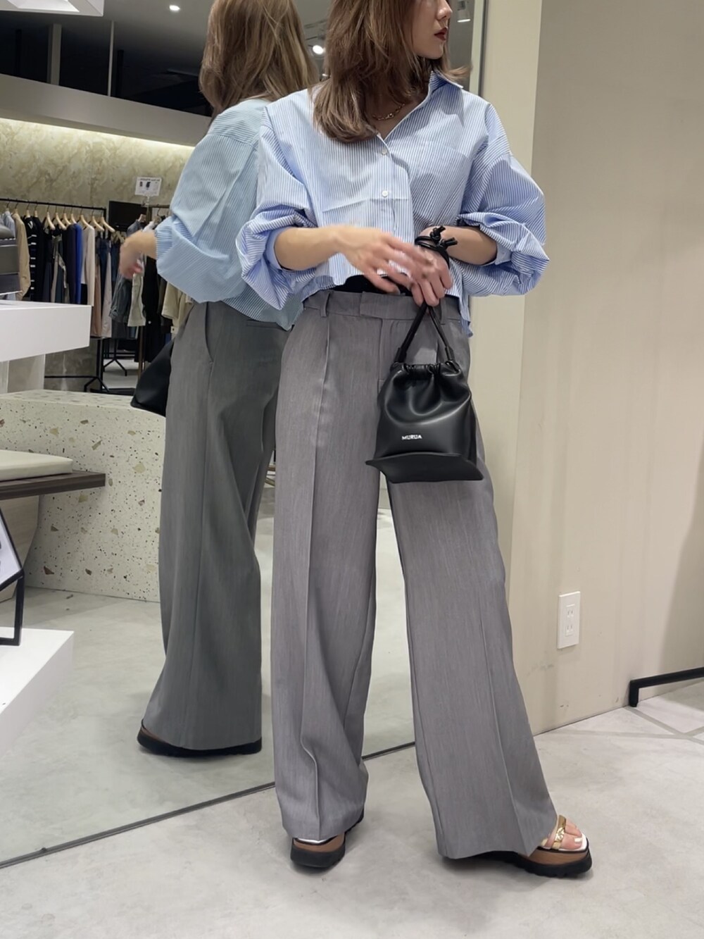 ブルー系のシャツ/ブラウス、グレー系のスラックス、その他のサンダルを着用したレディースの春コーディネートの3枚目の写真