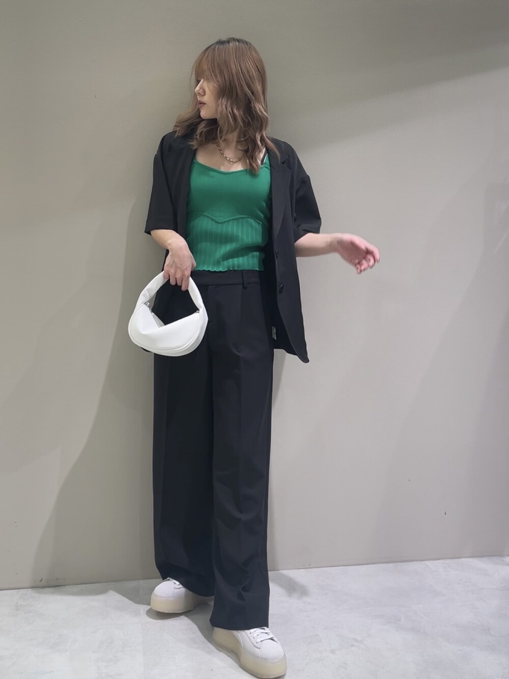 グリーン系のニット/セーター、グレー系のスニーカー、ブラック系のスラックスを着用したレディースの春コーディネートの2枚目の写真