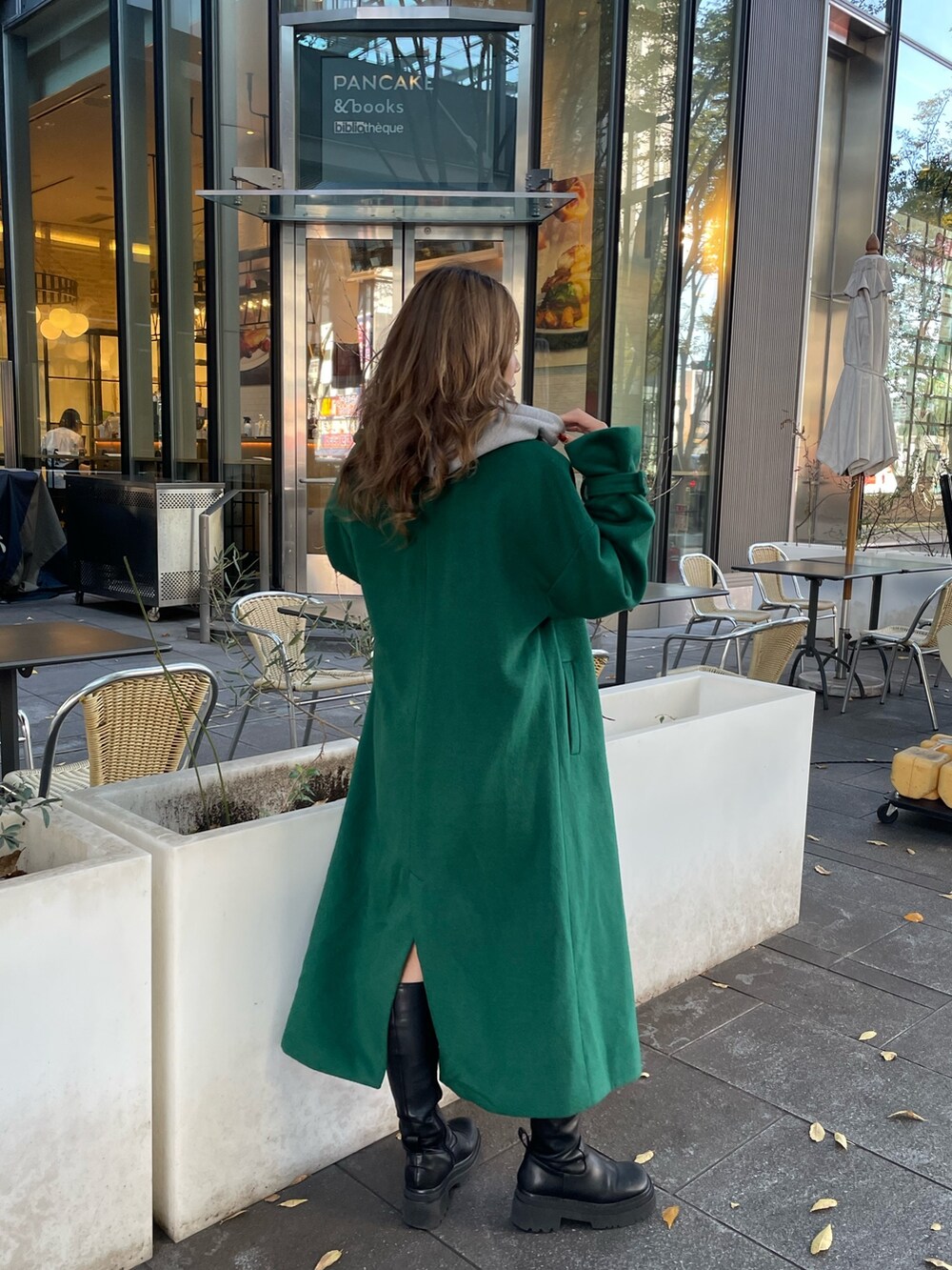 グリーン系のチェスターコート、ブラック系のブーツを着用したレディースの秋コーディネートの5枚目の写真