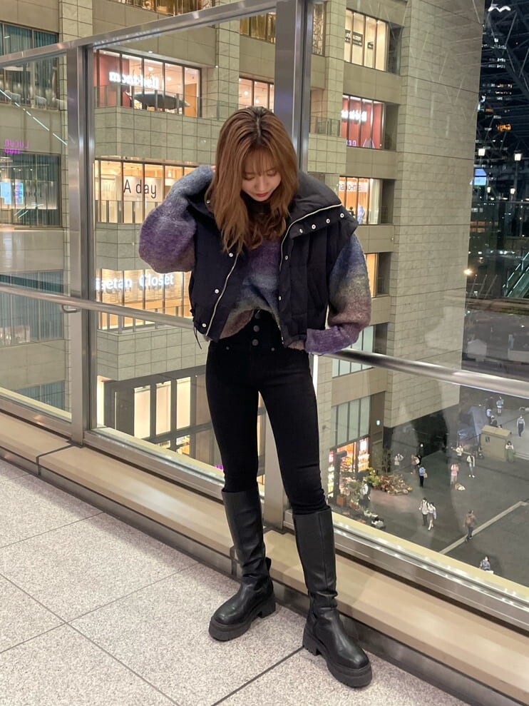 ブラック系のダウンベスト、ブラック系のブーツ、パープル系のニット/セーターを着用したレディースの秋コーディネートの5枚目の写真
