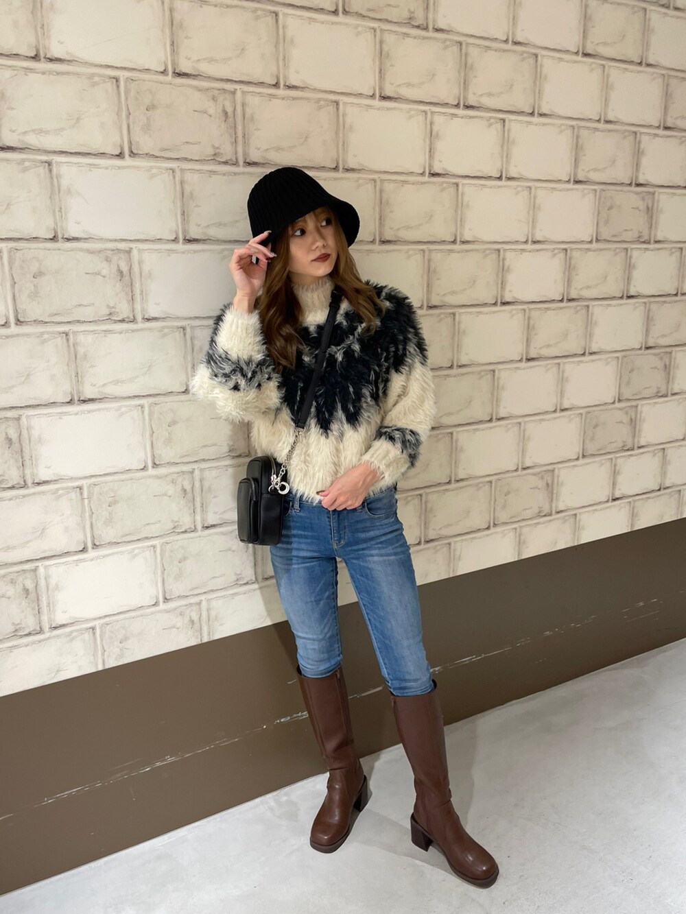 ホワイト系のニット/セーター、ブラウン系のブーツ、ブラック系のハットを着用したレディースの秋コーディネートの2枚目の写真