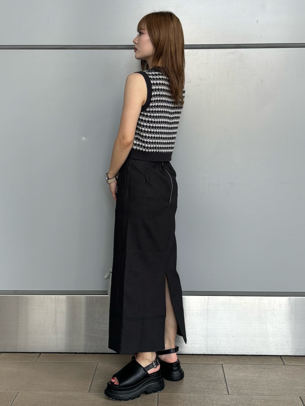 グレー系のニット/セーター、シルバー系のハンドバッグ、ブラック系のスカートを着用したレディースの夏コーディネートの2枚目の写真