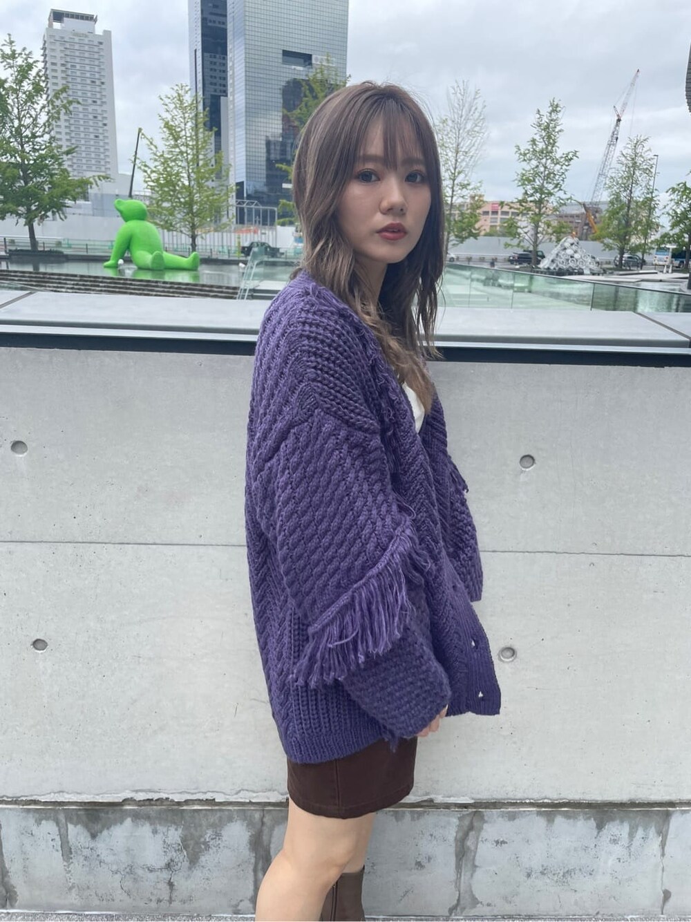 ブラウン系のスカート、ベージュ系のブーツ、パープル系のカーディガン/ボレロを着用したレディースの秋コーディネートの2枚目の写真