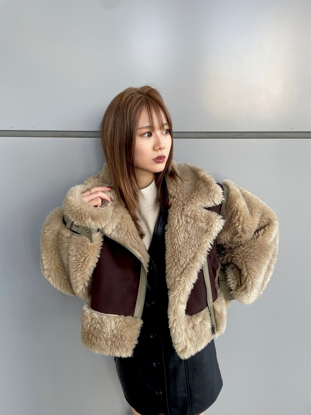 ブラック系のワンピース、ホワイト系のニット/セーター、ブラウン系のムートンコートを着用したレディースの冬コーディネートの4枚目の写真