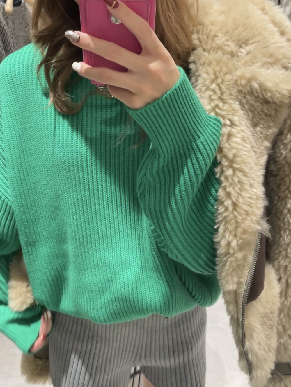 ブラウン系のムートンコート、グリーン系のニット/セーター、グレー系のスウェットパンツを着用したレディースの冬コーディネートの4枚目の写真